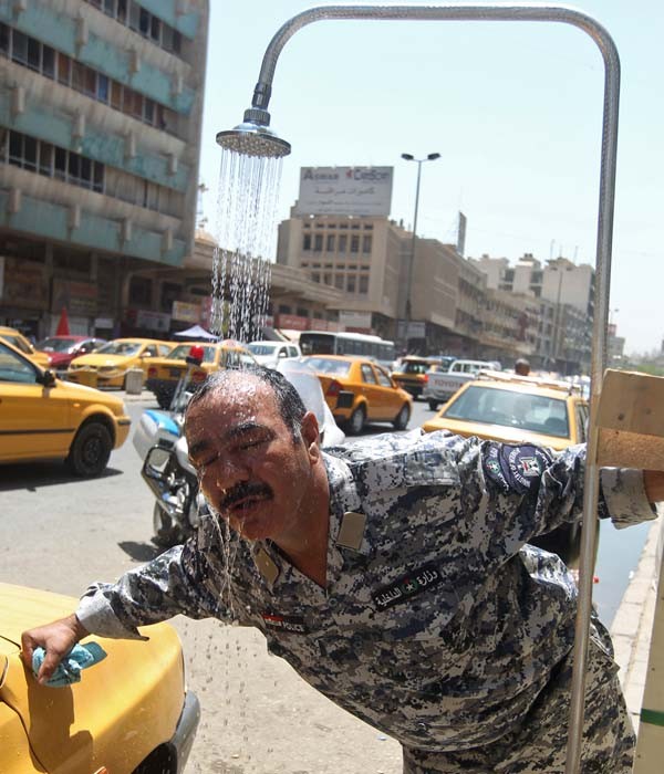 Policial toma uma ducha durante o expediente. (Foto: Ahmad Al-Rubaye/AFP)