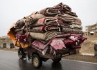 Homem conduz triciclo carregado de tapetes no Afeganistão (Behrouz Mehr/AFP)