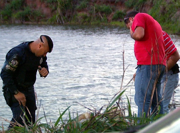 Policiais observam corpo de muher encontrado em mala num lago na região de Campinas (Foto: Reprodução EPTV)