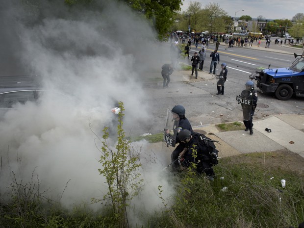 Policial tenta apagar chama causada por uma lata de gás lacrimogêneo durante confronto com manifestantes em Baltimore, na segunda (27) (Foto: AFP Photo/Brendan Smialowski)