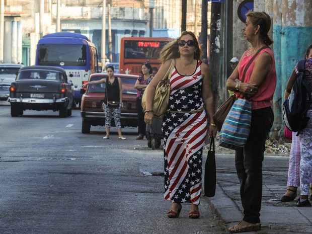 Mulher com vestido com as cores da bandeira dos EUA caminha nesta quinta-feira (17) pelo centro de Havana (Foto: YAMIL LAGE / AFP)