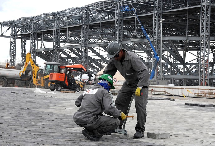 No Parque Olímpico, operários trabalham na Via Olímpica com a Arena do Futuro ao fundo (Foto: Andre Durão)