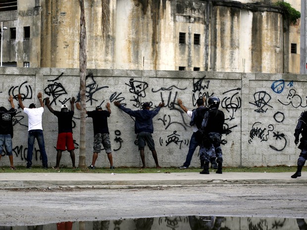 Homens são parados por policiais durante ocupação do conjunto de favelas de Manguinhos (Foto: Guto Maia/Frame/Estadão Conteúdo)