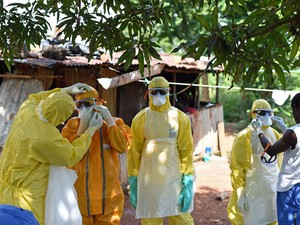 Trabalhadores de saúde da Cruz Vermelha de Serra Leoa se preparam para retirar um corpo de uma vítima de ebola de uma casa em Freetown nesta quarta-feira (12) (Foto: Francisco Leong/AFP)
