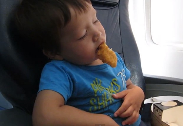 Menino foi 'vencido' pelo sono e dormiu enquanto comia nuggets no avião (Foto: Reprodução/YouTube/kharchenkog)