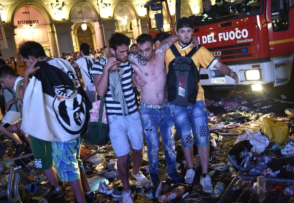 Homem é ajudado a sair da praça pelos amigos após a briga que feriu torcedores em Turim (Foto: Reuters)