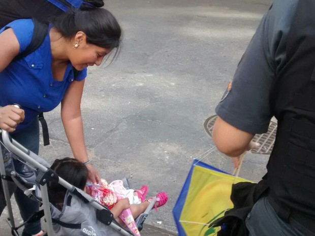 Moradora da comunidade recebe presente das mãos do policiail militar (Foto: Divulgação/Polícia Militar do Rio de Janeiro)