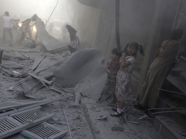 Crianças reagem ao lado de um cadáver sob escombros em local atingido em Douma, perto de Damasco, no domingo (3) (Foto: Bassam Khabieh/Reuters)