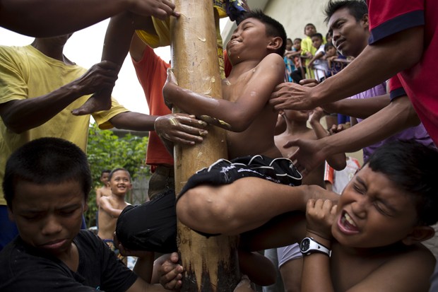 Grupo se esforça para tentar subir em pau de sebo durante competição na Malásia (Foto: Mohd Rasfan/AFP)