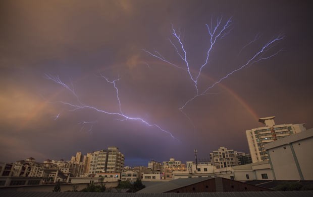 Uma foto feita em Haikou, na província de Hainan, na China, flagrou no mesmo momento um arco-íris e raios no céu durante uma tempestade. A cena foi fotografada no domingo (13). (Foto: China Daily/Reuters)