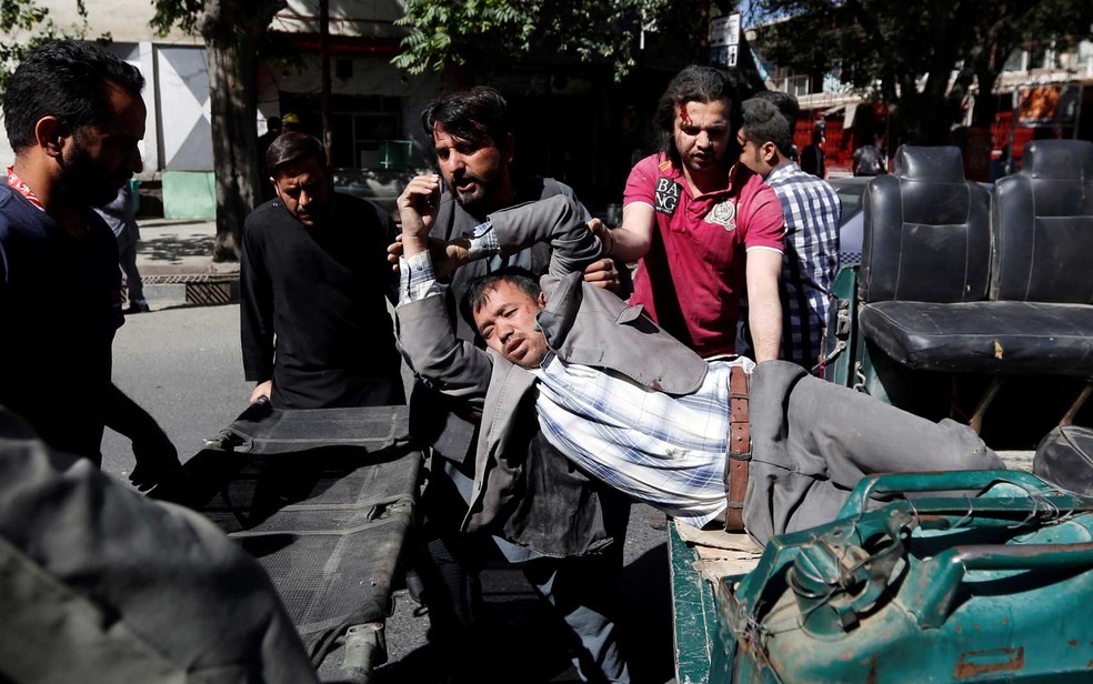 Homens movem um homem ferido para um hospital (Foto: Mohammad Ismail / Reuters)