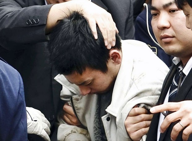 Yuta Sugimoto é levado por policiais após ser detido nesta quinta-feira (8). Perseguição de dois dias envolveu 4 mil policiais e 900 carros. Ele é acusado de ter participado de estupro coletivo (Foto: Kyodo News/AP)