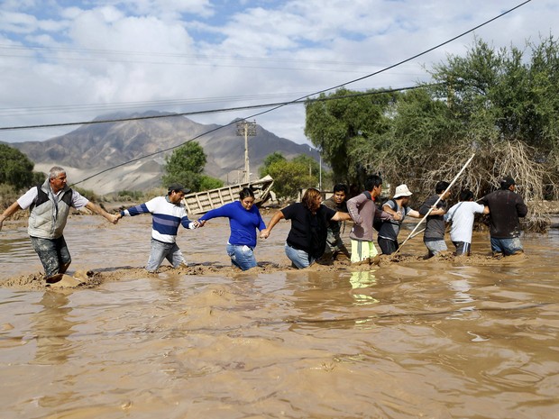 Moradores atravessam um rio inundado em Copiapo, no Chile. O número de mortos no país subiu para quatro após chuvas castigaram o norte (Foto: Ivan Alvarado/Reuters)