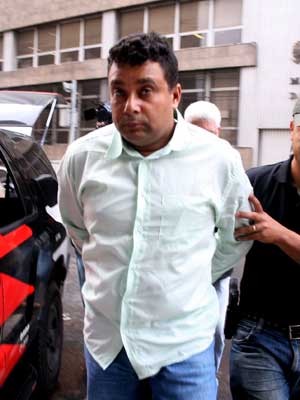 Vigia é levado por policiais para acareação no DHPP (Foto: Grizar Junio/AE) Vigia é levado por policiais para acareação no DHPP (Foto: Grizar Junio/AE)