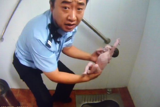 Policial segura bebÃª recÃ©m-nascido abandonado em banheiro pÃºblico de Pequim, na China, nesta segunda-feira (3) (Foto: AFP)