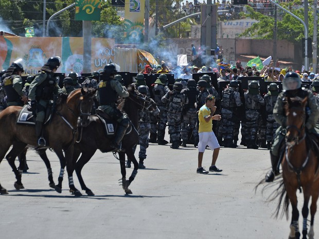 Homem que estava indo ao jogo da seleção brasileira em Fortaleza fica no meio da confusão em Polícia e manifestantes (Foto: Vanderlei Almeida/AFP)