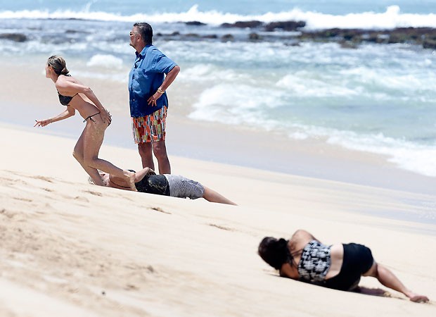 Após ajudar uma das babás, a modelo vai buscar água observada pelo pai, Gunther (de azul) (Foto: Grosby Group)