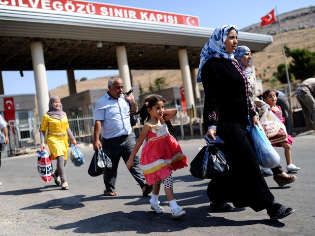 30/8 - Famílias sírias cruzam a fronteira e entram na Turquia pela passagem de Cilvegozu para se refugiar no país vizinho, com medo da tensão internacional que torna iminente um conflito com os EUA (Foto: Bulent Kilic/AFP)