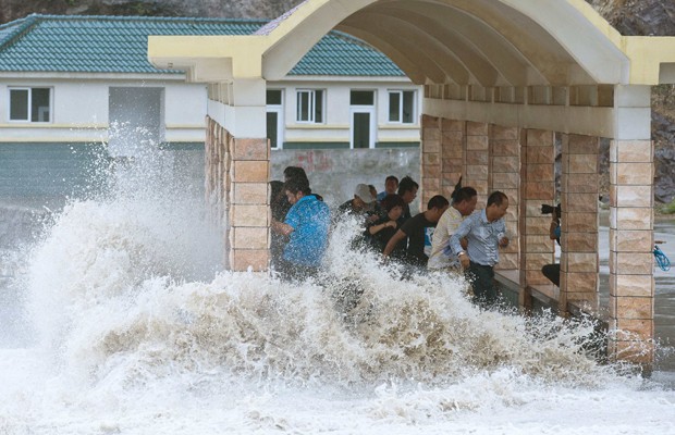 Pessoas tentam escapar de tempestade formada após a chegada do tufão Fitow (Foto: Reuters)