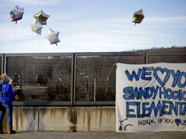 Jovem amarra balões em viaduto em homenagem às vítimas do massacre na escola Sandy Hook (Foto: AP)