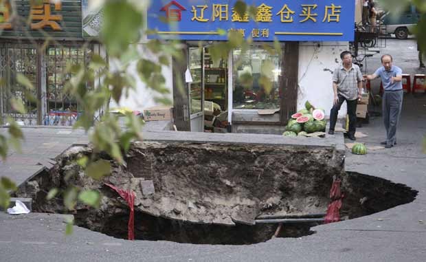 Buraco aberto durante obra de rua na China nesta terça-feira (14) (Foto: Xinhua/AP)