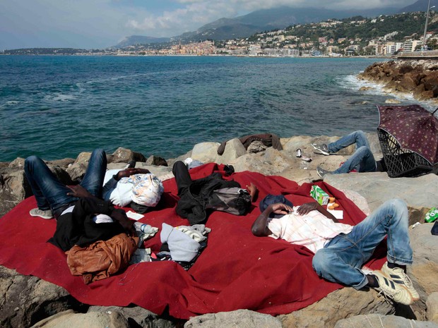 Imigrantes descansar no paredão de Saint Ludovic, na fronteira entre a França e a Itália no mar Mediterrâneo. No sábado (13), cerca de 200 imigrantes, principalmente da Eritreia e Sudão, tentaram atravessar a fronteira pela Itália e foram bloqueados  (Foto:  Eric Gaillard/Reuters)