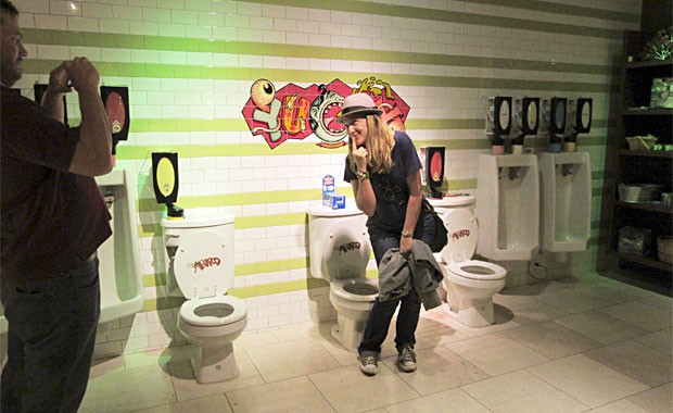 Turista tira foto perto de privadas e urinois que dispensam doces (Foto: Flávia Mantovani/G1)