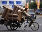 Homem dirige triciclo superlotado de sofás na China