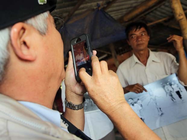 Nick Ut tira foto de homem segurando sua imagem icônica da Guerra do Vietnã nesa segunda-feira (8) em Trang Bang (Foto: AP Photo/Na Son Nguyen)