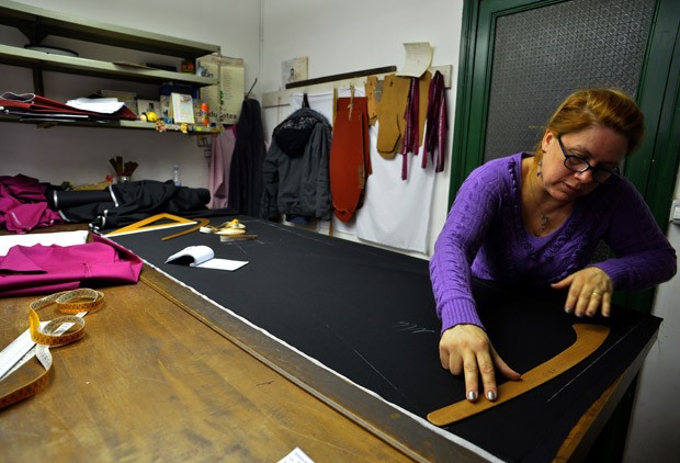 Funcionário trabalha em tecido na alfaiataria (Foto: Alberto Pizzoli/AFP)