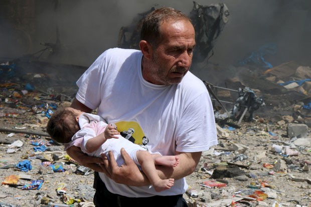 Homem segura bebê que sobreviveu a bombardeio com barris explosivos em Aleppo nesta quarta-feira (3) (Foto: Abdalrhman Ismail/Reuters)