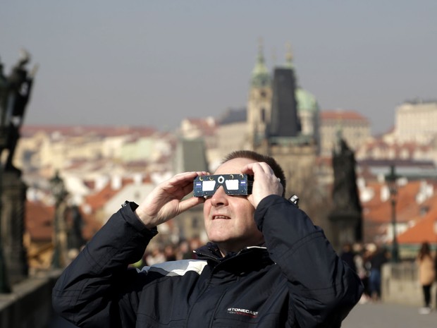 Homem tenta observar eclipse solar em Praga, na República Tcheca, nesta sexta-feira (20) (Foto: Petr David Josek/AP)