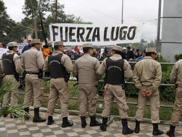 Policiais guardam o prédio do Congresso do Paraguai, em Assunção, nesta sexta-feira (22), diante de manifestantes que apoiam o presidente Fernando Lugo (Foto: AFP)
