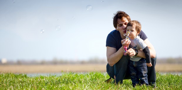 Pai e filho brincando de bolhas de sabão ao ar livre (Foto: Shutterstock)