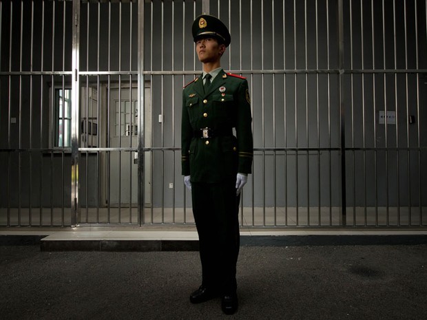 Guarda mantém posição em frente à grade da entrada principal do Centro de Detenção nº 1 durante uma visita da imprensa guiada pelo governo em Pequim, na China. A rara visita ao local ocorre próximo ao 18º Congresso do Partido COmunista Chinês. (Foto: Ed Jones/AFP)