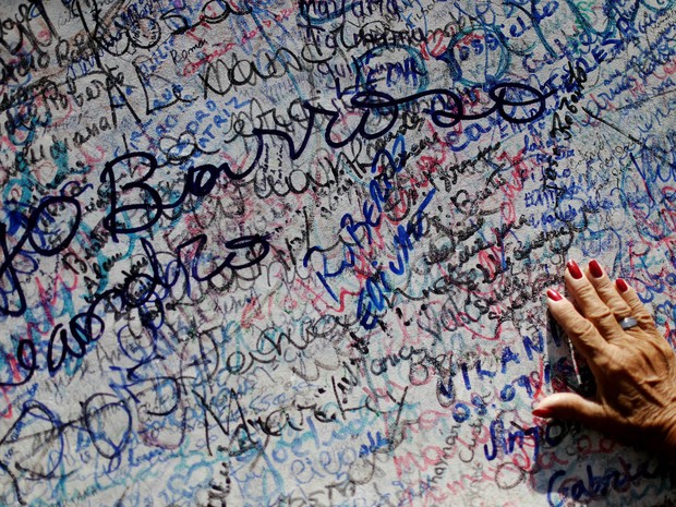 Contra orientação dos administradores do Horto, fiéis escrevem nomes na base da estátua de padre Cícero. Eles acreditam que o registro traz a realização de promessas (Foto: Ueslei Marcelino/Reuters)