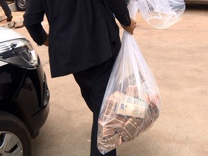 Policial carrega saco com dinheiro encontrado em casa de investigador em Campinas (Foto: Reprodução EPTV)