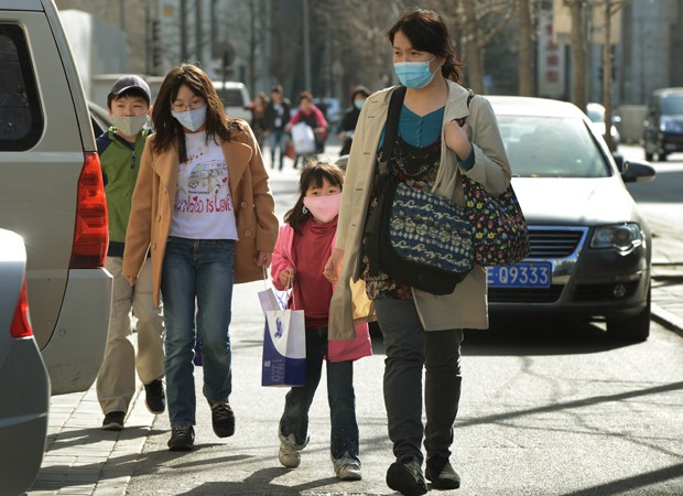 Família chinesa usa máscaras para se proteger da poluição em Pequim (Foto: Mark Ralston/AFP)