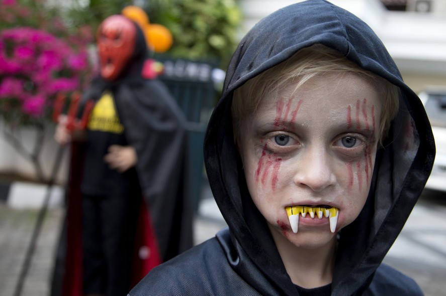 Na Indonésia, um menino e prepara para passar pelas casas pedindo doces no Dia das Bruxas nas ruas de Jacarta