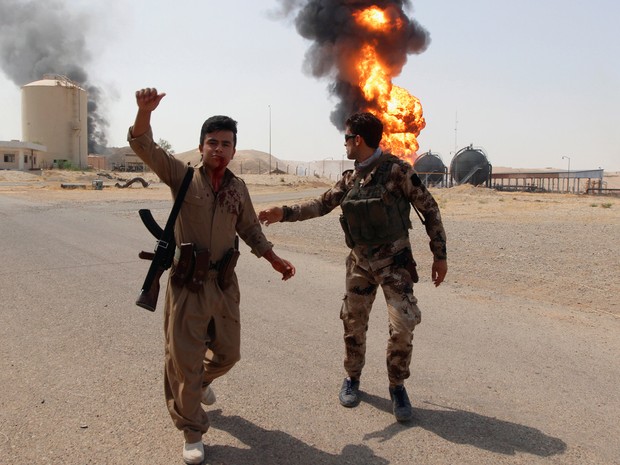  Membro das forças curdas ferido é fotografado em frente a fogo que acometeu a estação de petróleo Bai Hassan, no Iraquem, após ataque atribuído ao Estado Islâmico  Membro das forças curdas ferido é fotografado em frente a fogo que acometeu a estação de p (Foto: Reuters/Ako Rasheed)