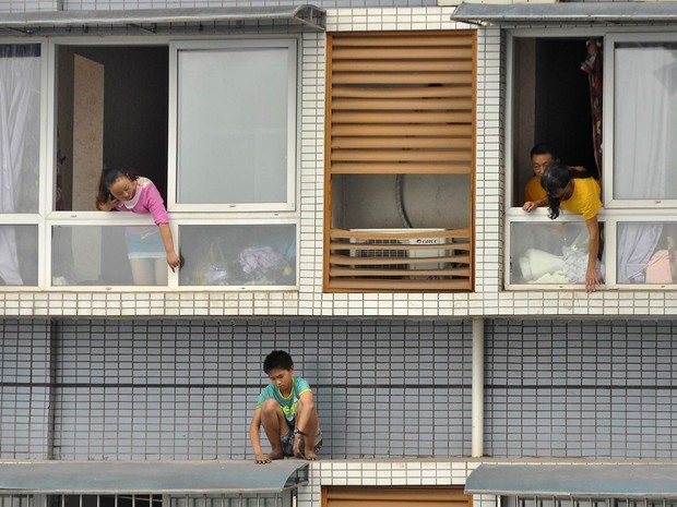 Familiares tentam convencer um menino de 12 anos a voltar para dentro do apartamento no 11º andar em Yibin, China. Ele estava com medo de ser punido por não terminar o dever de casa. Após 2 horas, ele voltou, convencido pela família e pela polícia (Foto: Reuters/Stringer)
