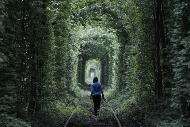 Mulher caminha no 'túnel do amor' ucraniano neste domingo (13) na cidade de Klevan (Foto: Gleb Galanich/Reuters)