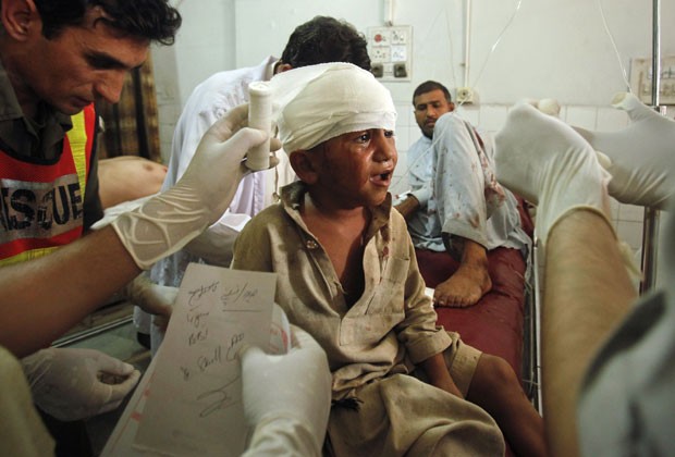 Criança é atendida por paramédicos após atentado em mercado paquistanês (Foto: Fayaz Aziz/Reuters)