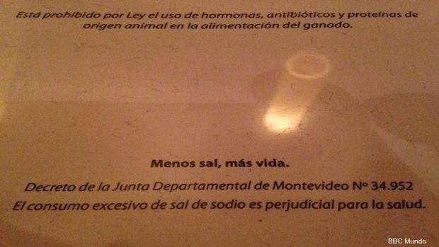  Bares e restaurantes de Montevidéu não podem colocar saleiros nas mesas sem que os clientes peçam, e os cardápios devem trazer advertências como esta.  (Foto: BBC)