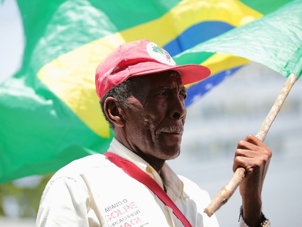 Homem com boné de movimento agrário agita bandeira do Brasil duranrte manifestação pró-Dilma em Maceió (Foto: Jonathan Lins/G1)