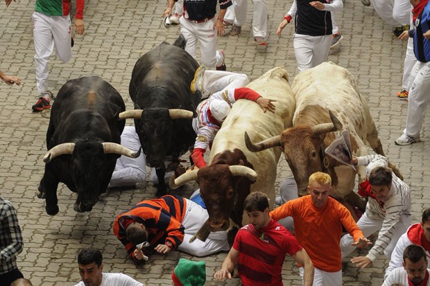 Participantes da festa de San Firmino tentam fugir de touros nesta quinta-feira (10) em Pamplona (Foto: Pedro Armestre/AFP)