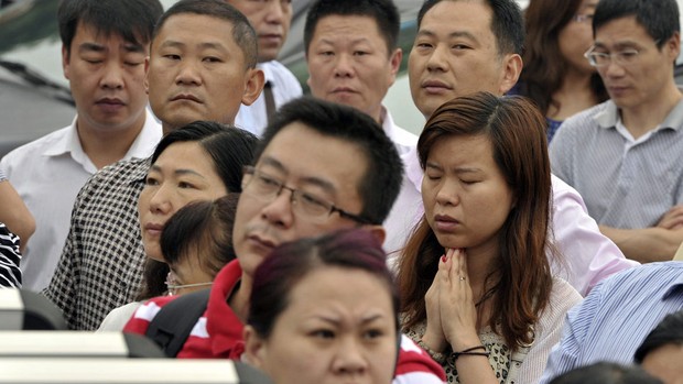 Mãe reza enquanto filha faz a prova em Nanjing (Foto: Reuters)