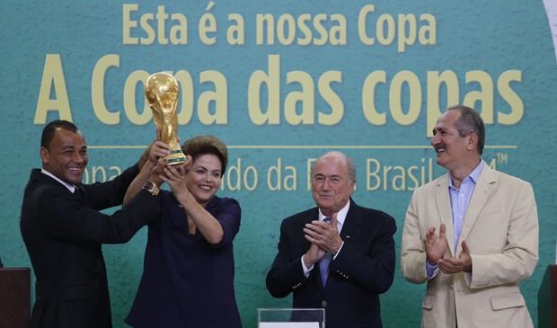 O ex-jogador e campeão do mundo Cafu (e) e a presidente Dilma Rousseff levantam a Taça da Copa do Mundo apresentada pelo presidente da Fifa, Joseph Blatter (2º/d); ao lado o ministro do Esporte, Aldo Rebelo (d) (Foto: Dida Sampaio/Estadão Conteúdo)