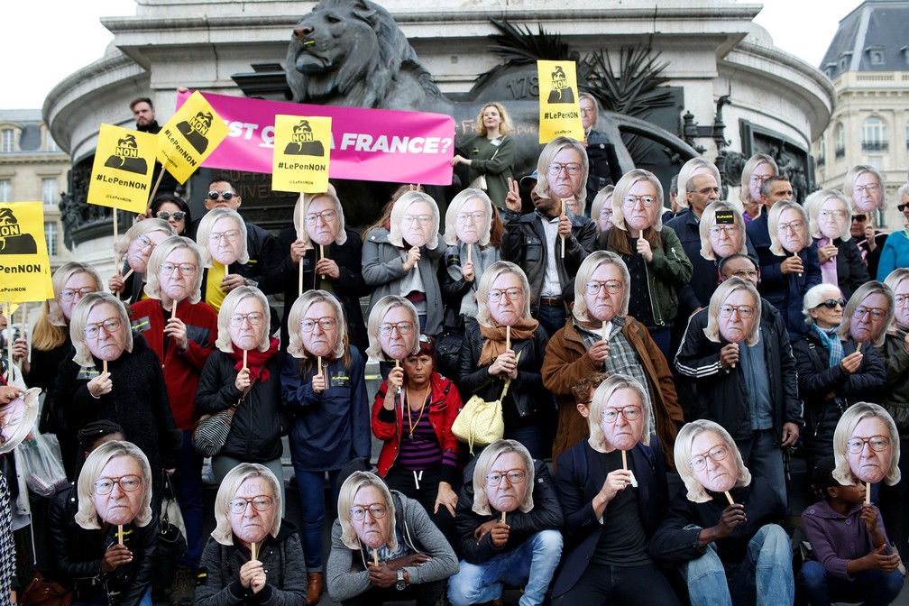 Ativistas usam máscara de Jean-Marie Le Pen, fundador do partido de extrema-direita da França, com o o cabelo da filha dele, Marine Le Pen, candidata à presidente do país, durante marcha do Dia do Trabalhador em Paris nesta segunda-feira, dia 1º de maio de 2017 (Foto: Gonzalo Fuentes/Reuters)