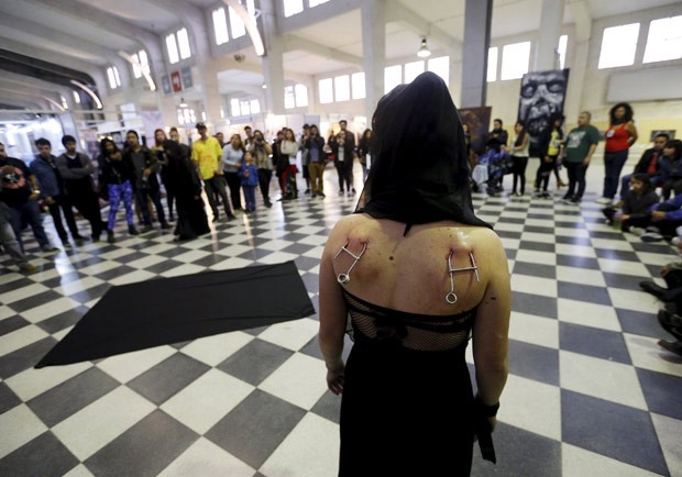 Imagem mostra ganchos colocados nas costas de mulher durante evento de suspensão corporal (Foto: Rodrigo Garrido/Reuters)